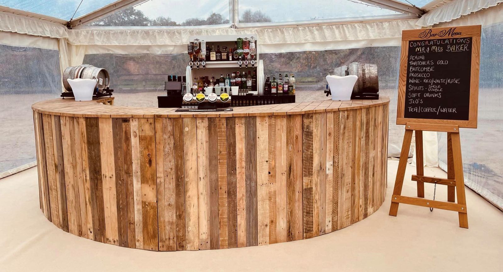 Curved rustic reclaimed timber bar inside a marquee